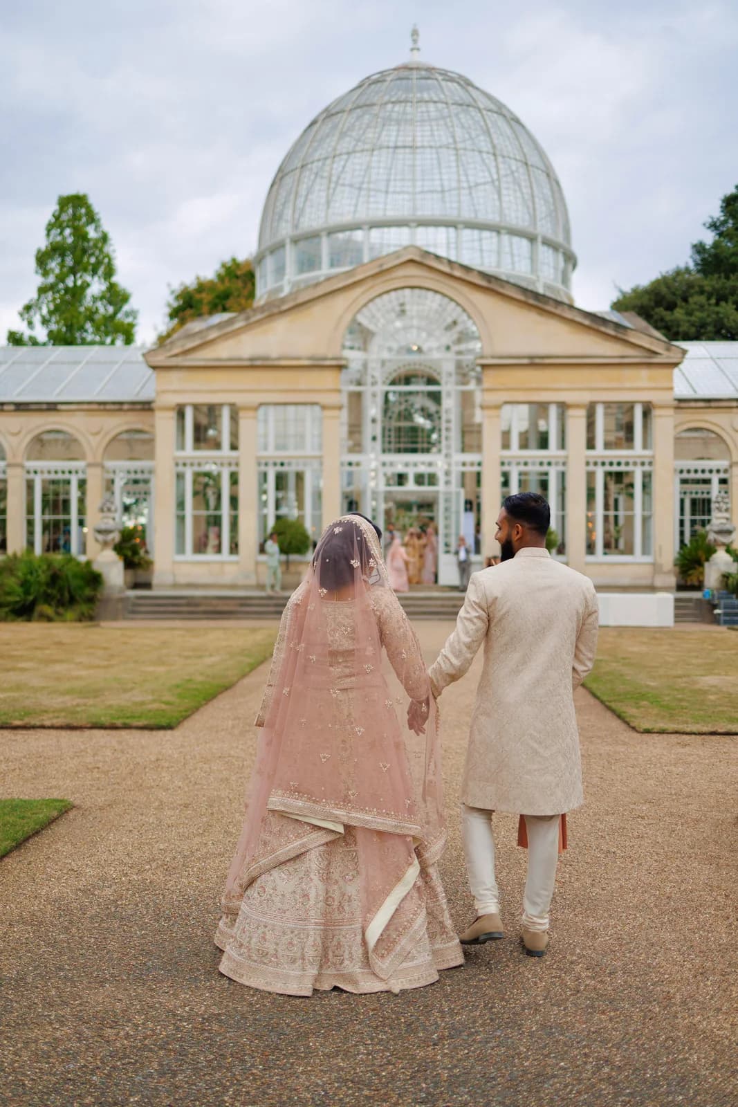 A couple holding hands outside a glasshouse